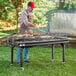 A man grilling food on a Backyard Pro heavy-duty steel charcoal grill.